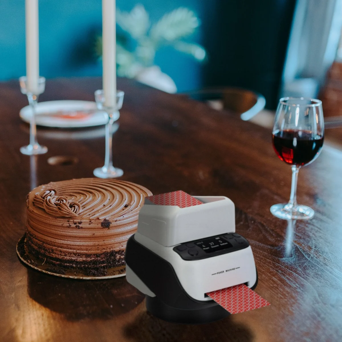 Distributeur automatique de cartes rechargeable, 8 joueurs, sur une table de salle à manger, à côté d'un gâteau et de verres de vin (mise en scène)