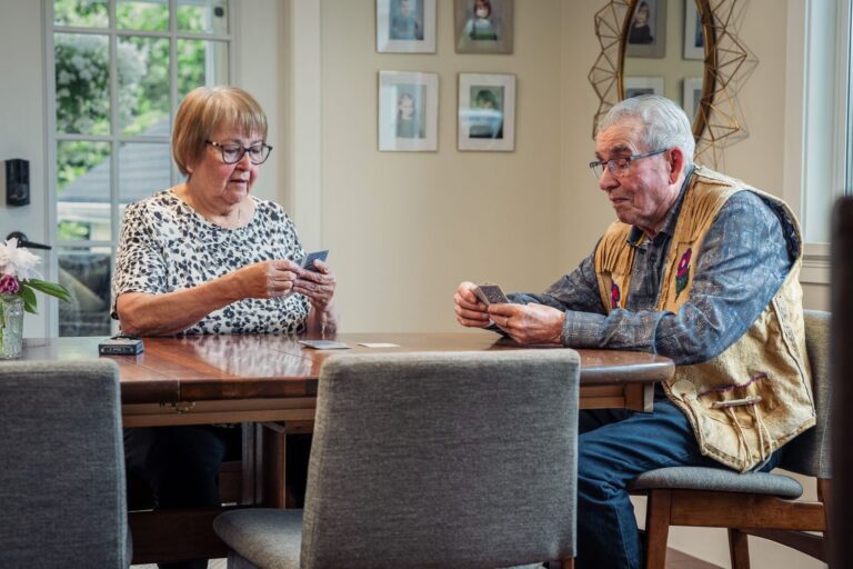 Un couple de seniors joue aux cartes à la table de la salle à manger