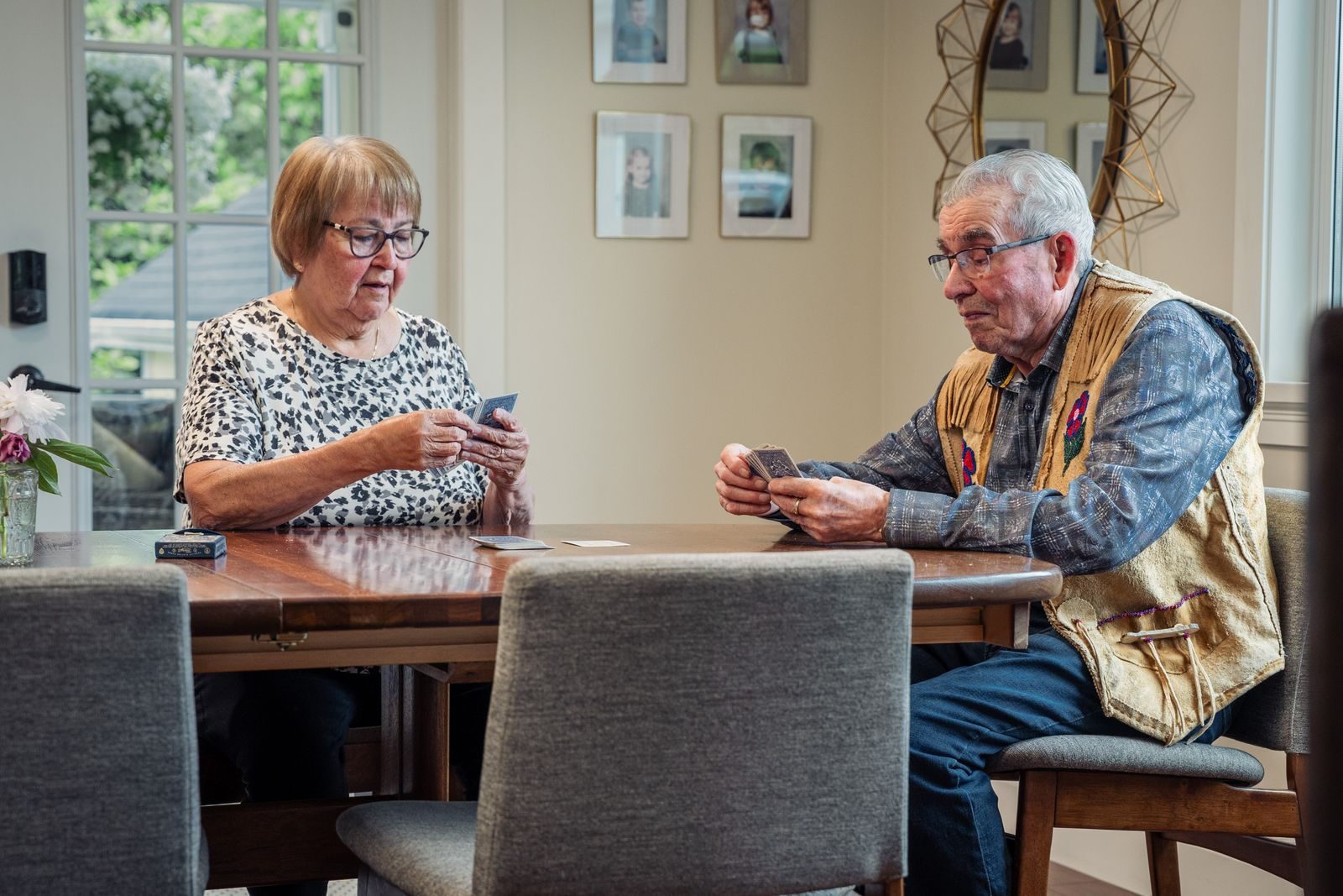 Un couple de seniors joue aux cartes à la table de la salle à manger