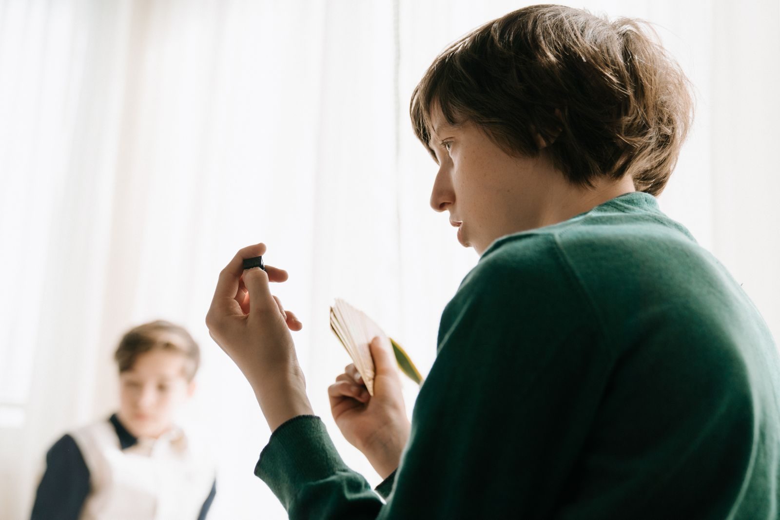 Deux enfants jouent à un jeu de cartes, l'un d'eux réfléchit en regardant sa main