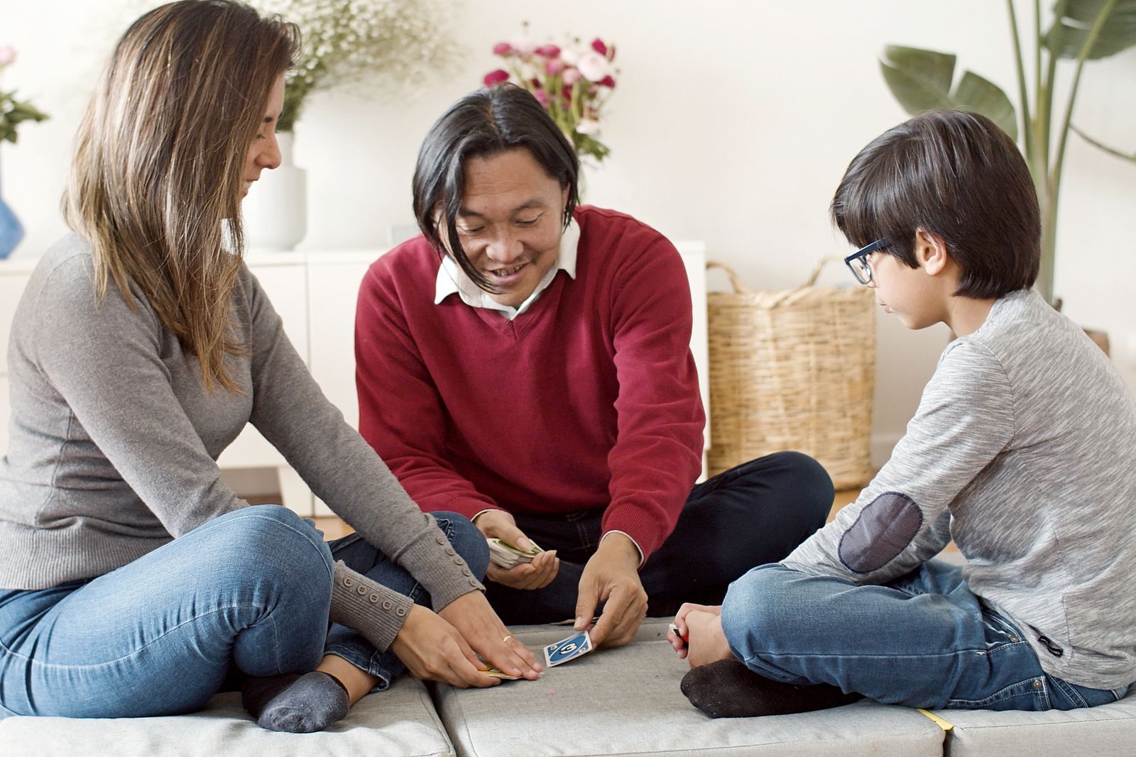 Une famille joue aux cartes assise par terre dans le salon