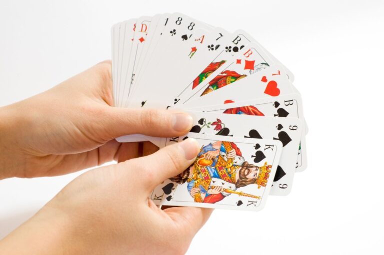 Une main tient un jeu de cartes à jouer ouvert en éventail