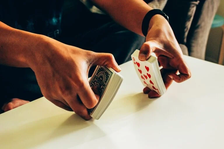 Deux mains font un mélange américain : les deux moitiés du paquet s'entrelacent au-dessus d'une table blanche