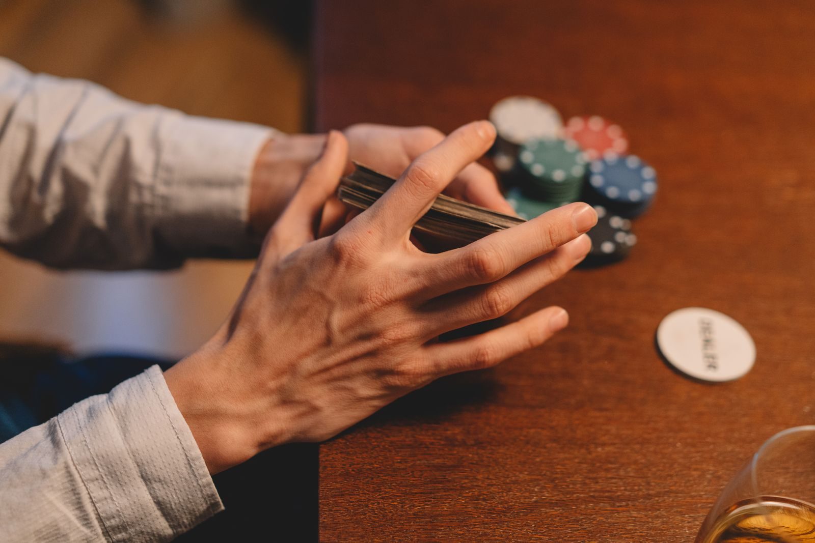 Un joueur tient le paquet de cartes au-dessus de la table, à côté du bouton du donneur et de piles de jetons