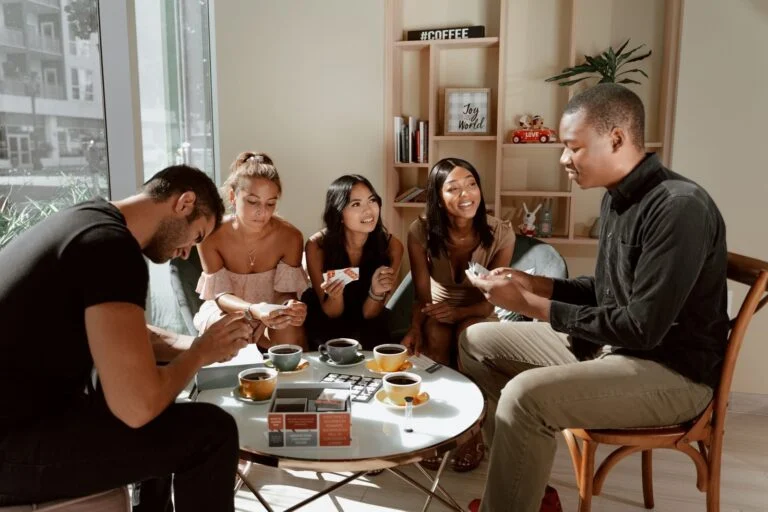 Un groupe d'amis joue aux cartes autour d'une petite table dans un salon convivial