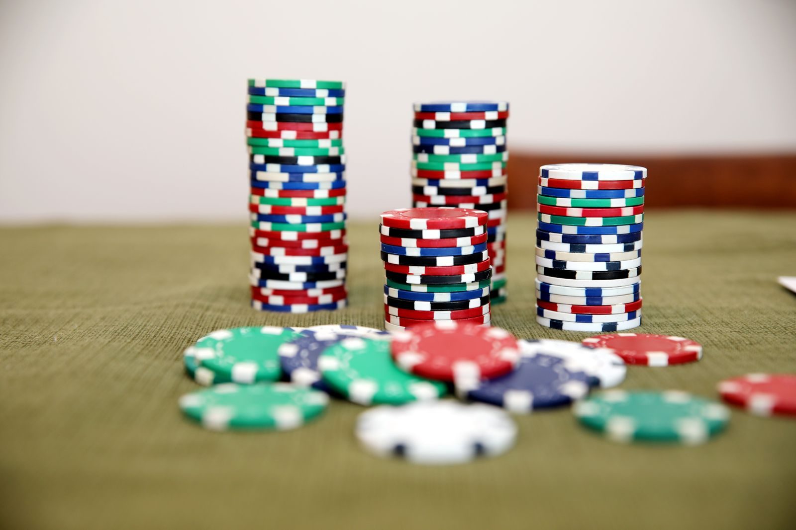 Piles de jetons de poker rouges, bleus, verts et blancs sur un tapis de jeu vert